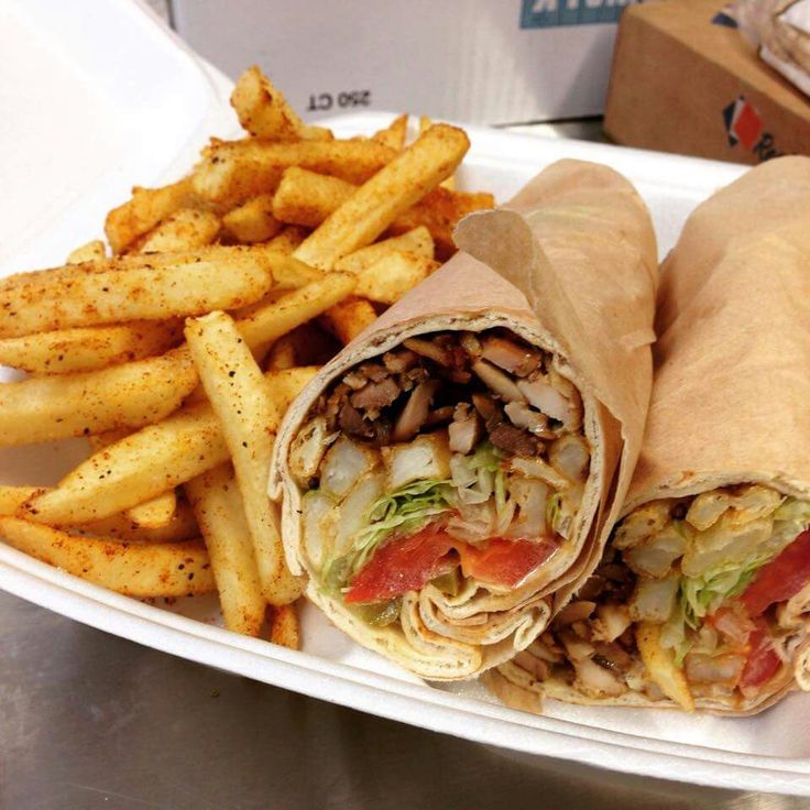 a sandwich and french fries on a paper plate with a cardboard box in the background