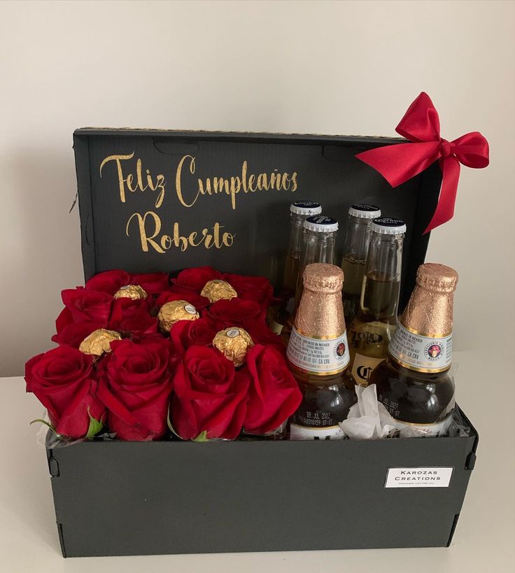 two bottles of champagne and roses in a black box with red ribbon on the top