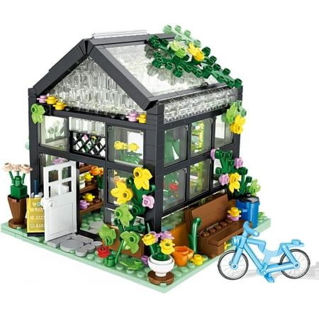 a toy house with flowers and plants on the outside, next to a lego bicycle