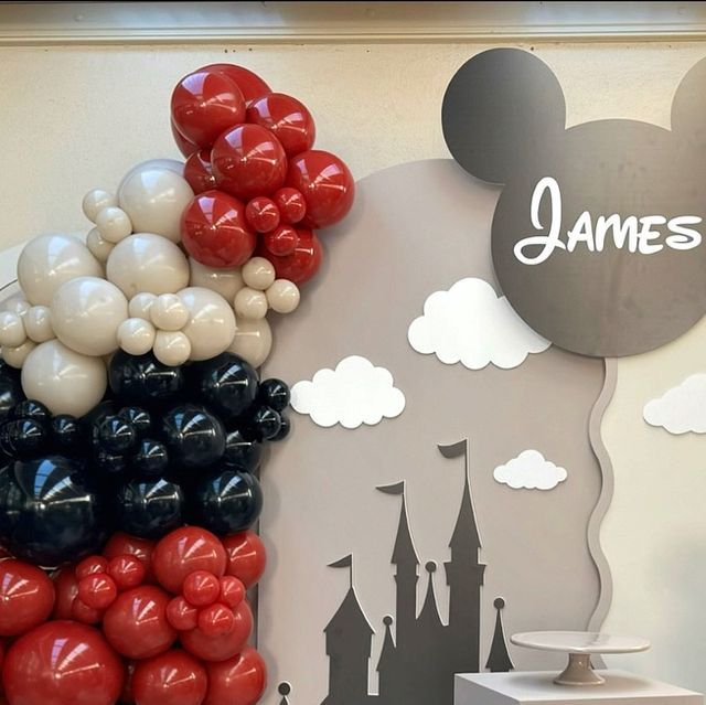 a mickey mouse balloon wall hanging in front of a castle with the name james written on it