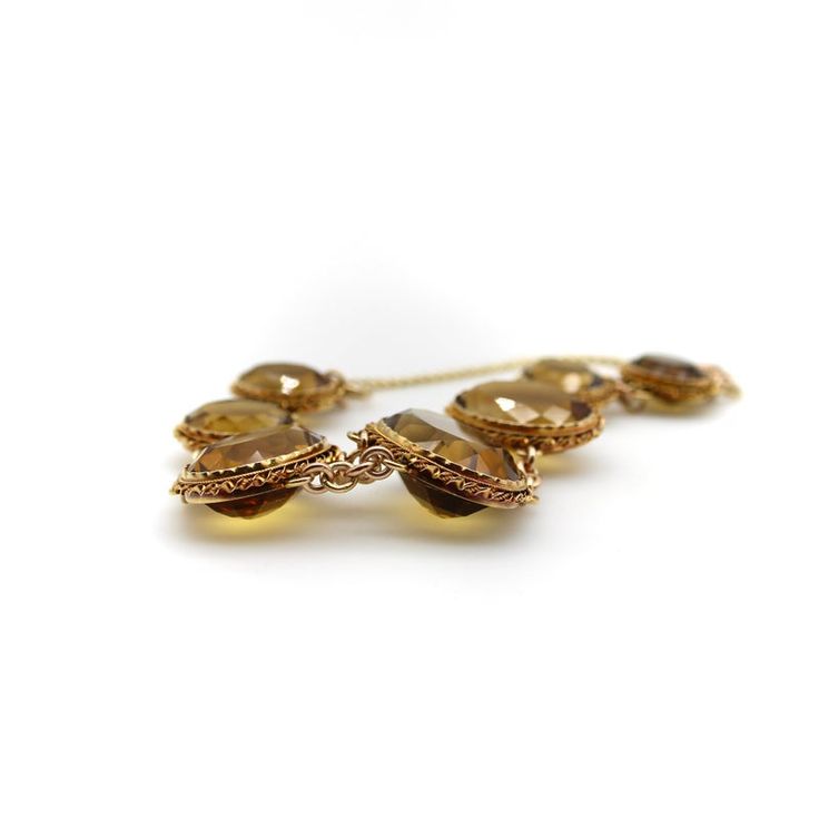 This is part of Chairish’s Fine Jewelry assortment.  What makes this Victorian 14k gold bracelet so beautiful are the magnificent, well-matched amber hued citrine gemstones that have stunning presence on the wrist. The stones graduate in size with the largest stone as the centerpiece, measuring 22 x 16 x 10.5 mm. The presentation is rich, warm facets of citrines that dominate the overall look of the bracelet. The stones are bezel set into gold that is crimped around the edges, framed by Etruscan Timeless Citrine Gemstone Jewelry, Luxury Amber Jewelry For Formal Occasions, Elegant Citrine Jewelry In Amber, Timeless Citrine Jewelry For Formal Occasions, Elegant Brown Jewelry With Polished Finish, Elegant Smoky Quartz Jewelry For Anniversary, Elegant Brown Polished Jewelry, Elegant Faceted Citrine Bracelets, Classic Smoky Quartz Jewelry For Formal Occasions