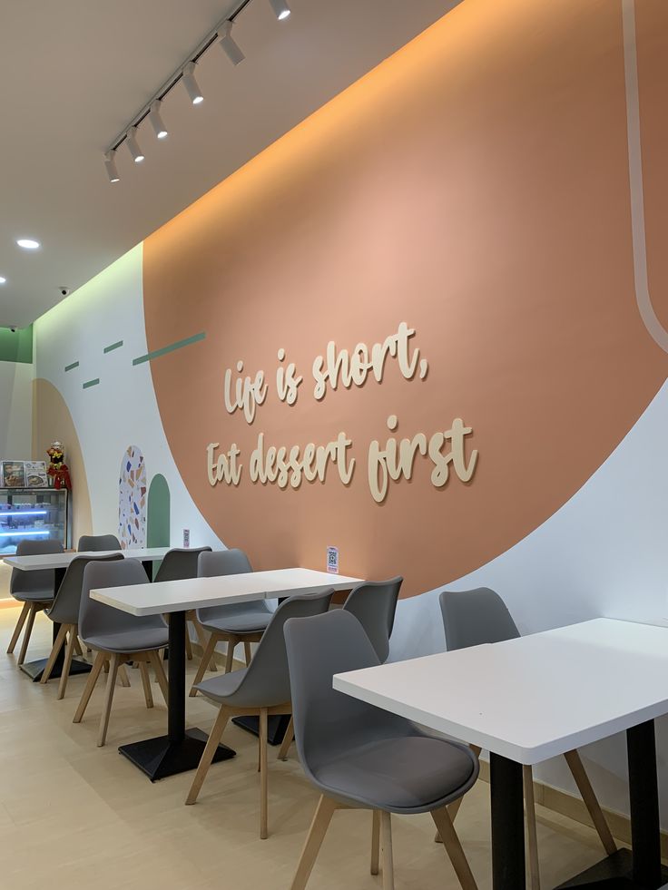 an empty restaurant with tables and chairs in front of a wall that says life is short, eat dessert first