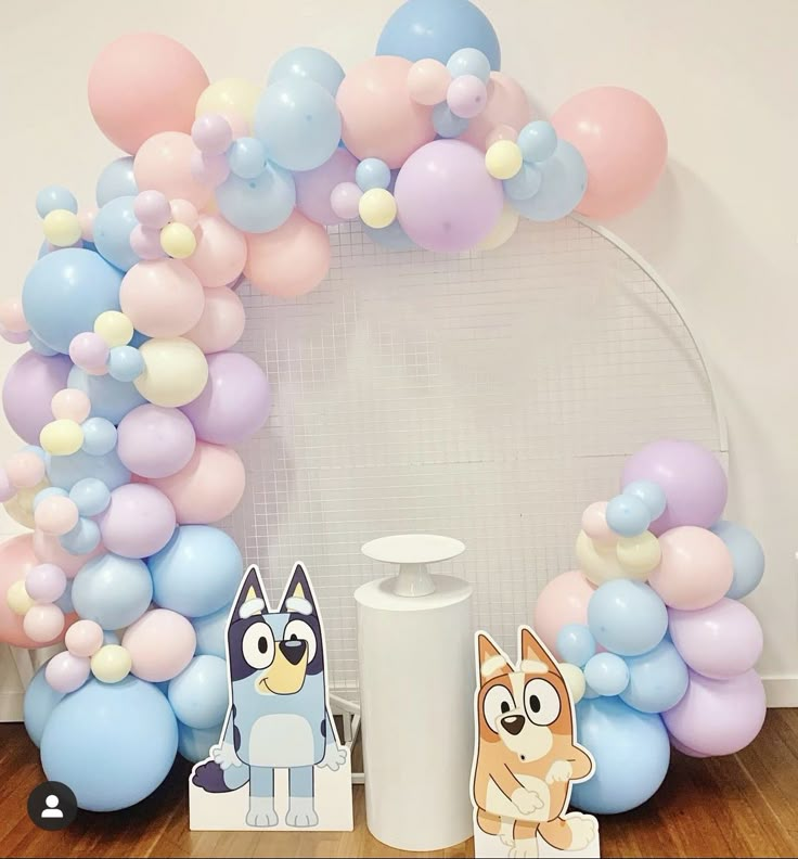 some balloons are on the floor and one is in front of a balloon arch with an animal figure