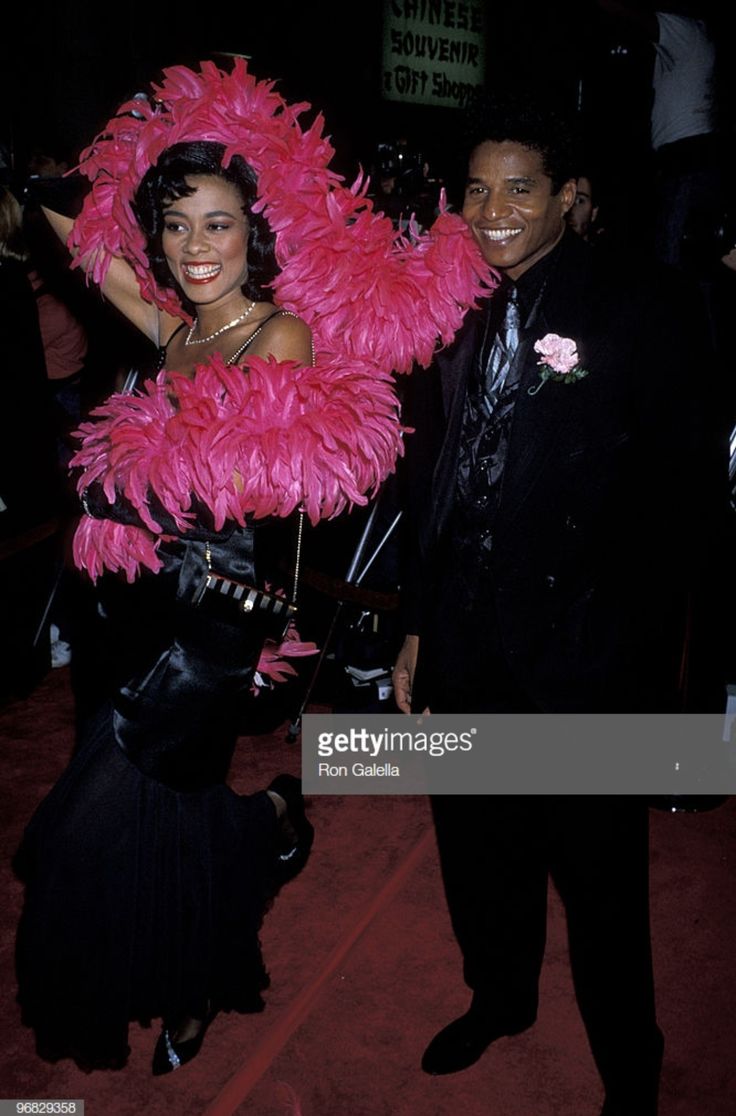 a man and woman dressed in pink feathers pose for a photo at an event together