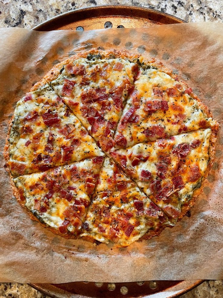 a pizza sitting on top of a wooden pan covered in cheese and bacon toppings