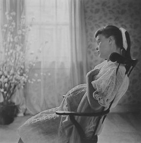 an old black and white photo of a woman sitting in a chair