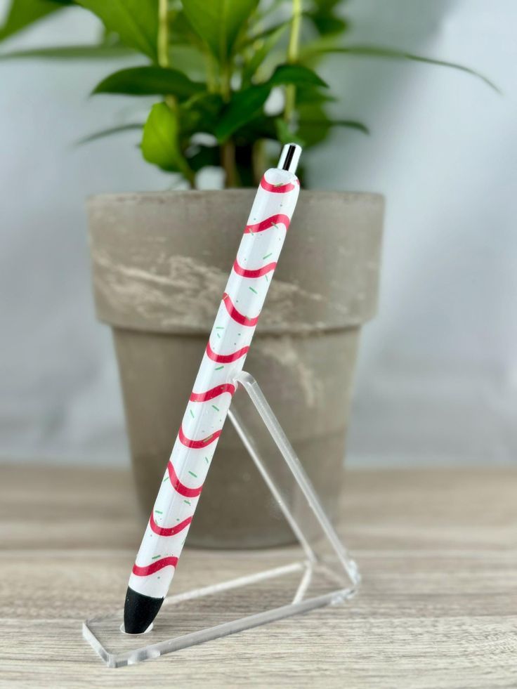 a red and white striped pen sitting on top of a table next to a potted plant