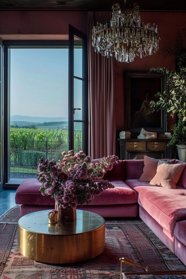 a living room filled with pink couches and a chandelier hanging from the ceiling