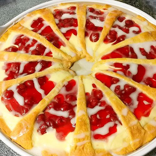 a pie with cherry toppings and white icing