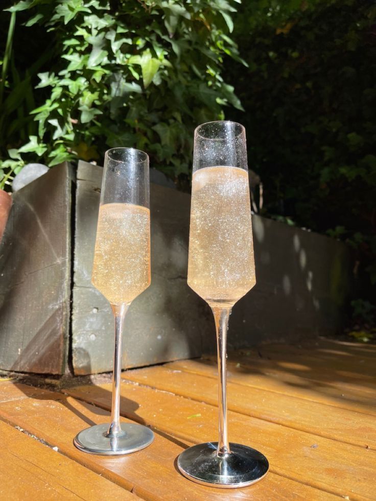 two champagne flutes sitting on top of a wooden table