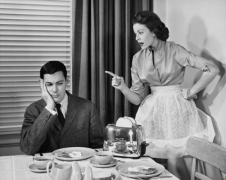 a man and woman sitting at a table in front of a tea kettle with plates on it