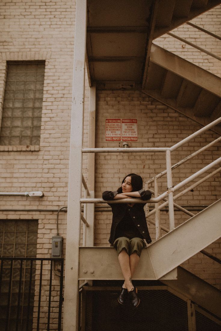 a woman sitting on top of a metal stair case