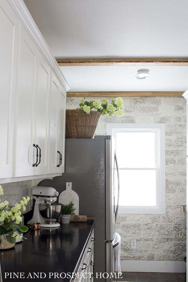 a kitchen with white cabinets and black counter tops is pictured in this image, there are flowers on the window sill