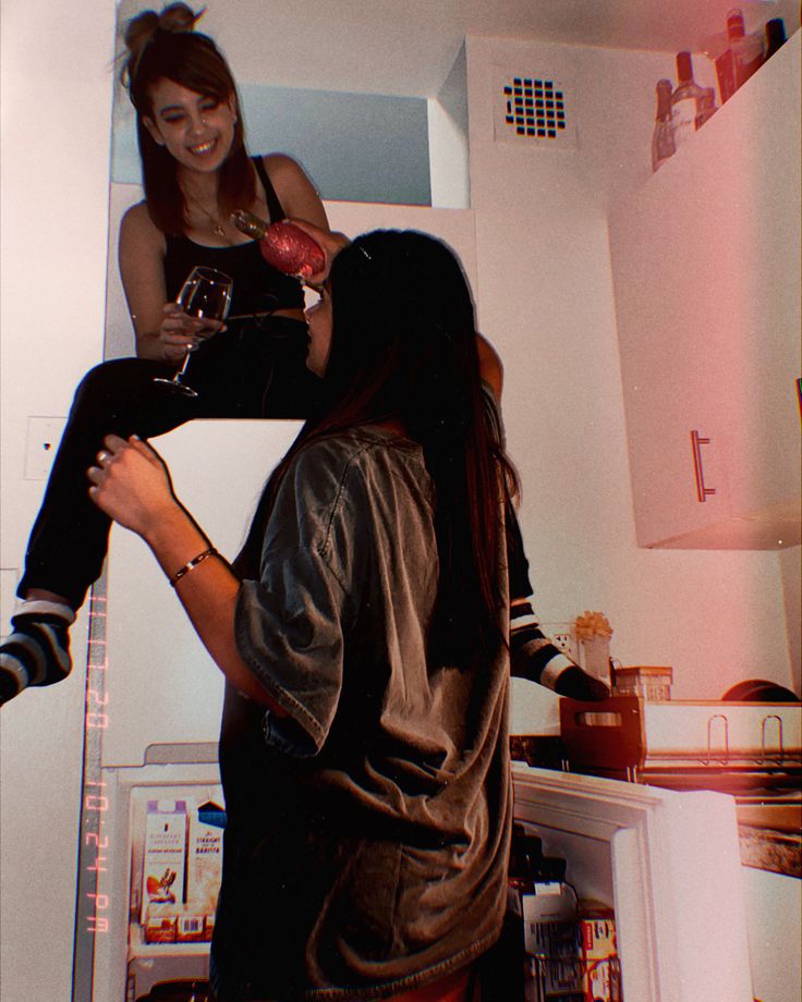 two women standing in a kitchen next to an open refrigerator