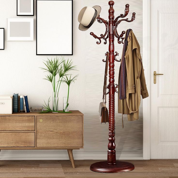 a coat rack with hats and coats hanging on it next to a dresser in a white room