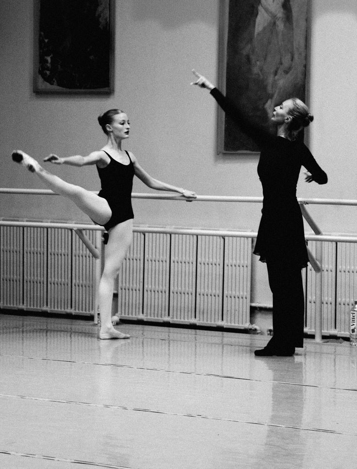 two ballerinas in black leotards and one has her arms stretched out