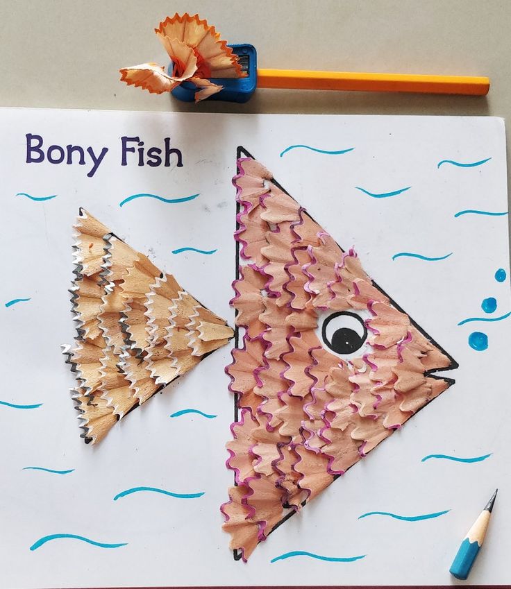 two fish made out of pencils sitting on top of a piece of paper