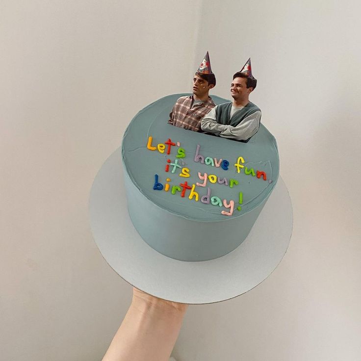 two men sitting on top of a blue birthday cake with the words let's love fun it's your birthday