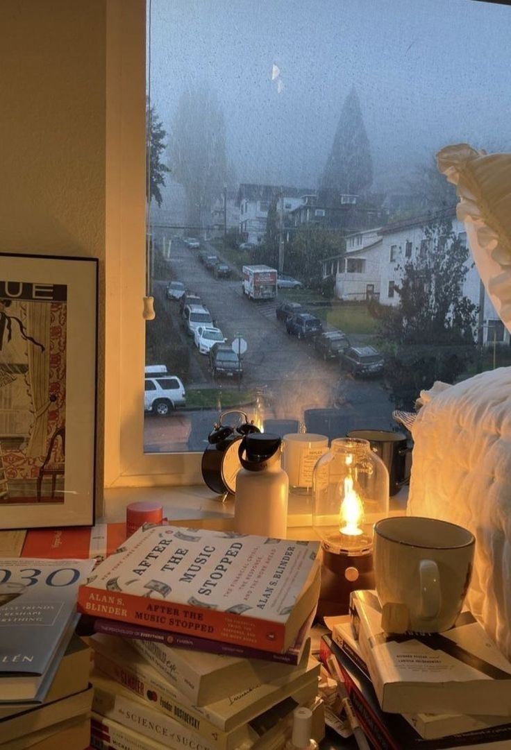 a window sill filled with books and candles next to a lamp on top of a table