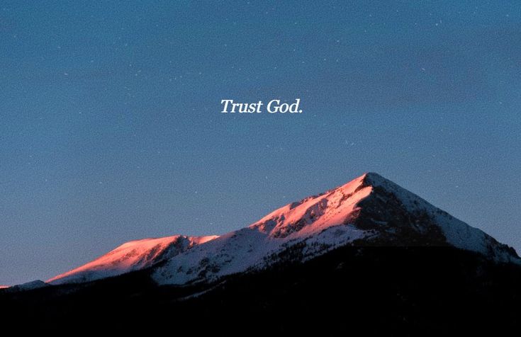 the words trust god are lit up in the sky above a snow - capped mountain