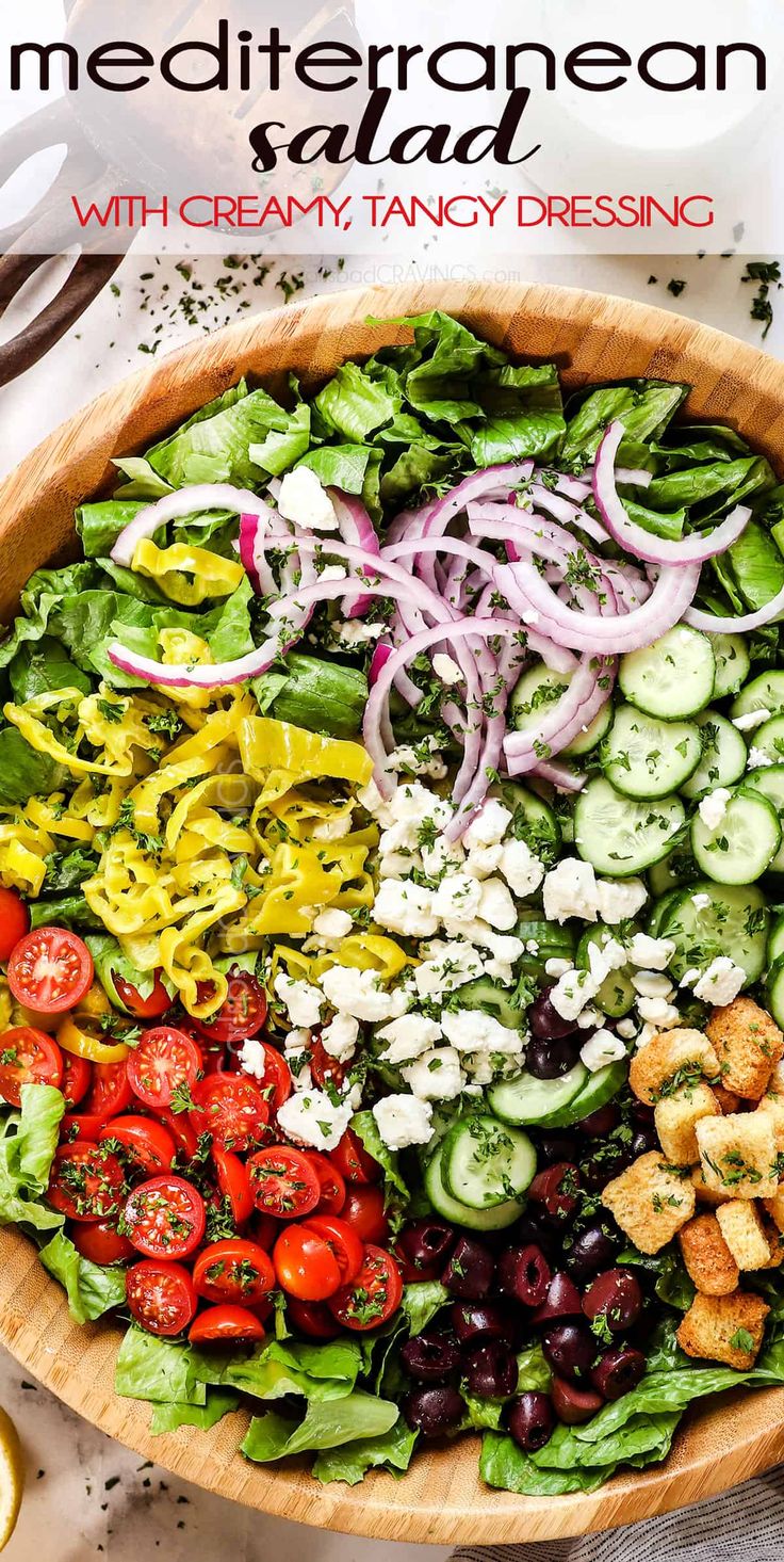 a salad with croutons, tomatoes, cucumbers and olives in a wooden bowl