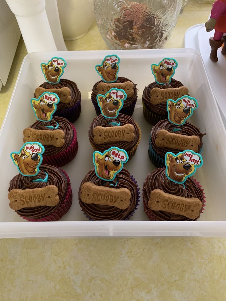 cupcakes with frosting in the shape of dogs on them are arranged in a tray