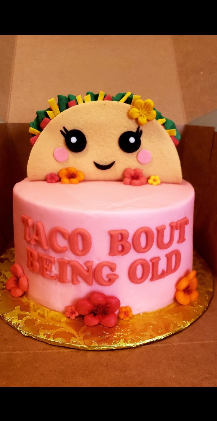 a pink cake decorated with an image of a taco and the words being old