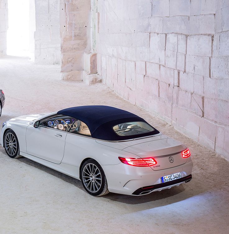 two cars parked next to each other in an empty room with stone walls and flooring