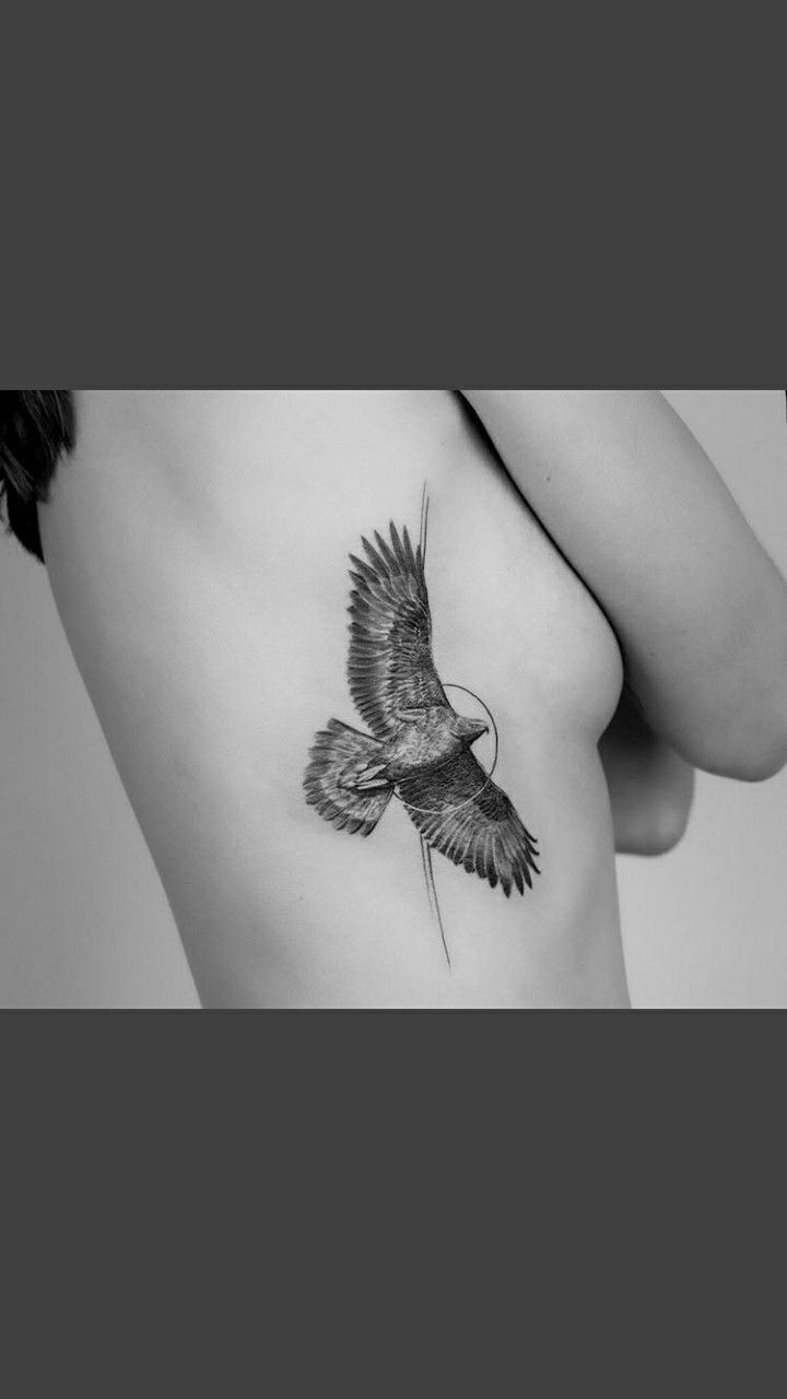 a black and white photo of a woman's back with a bird tattoo on it