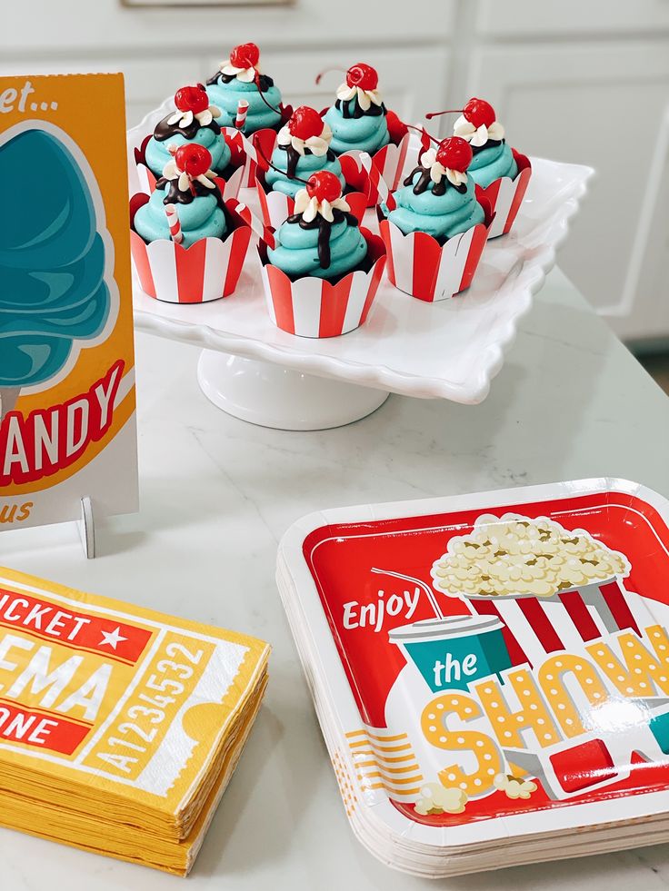 cupcakes and candy are sitting on a table next to a box of candy