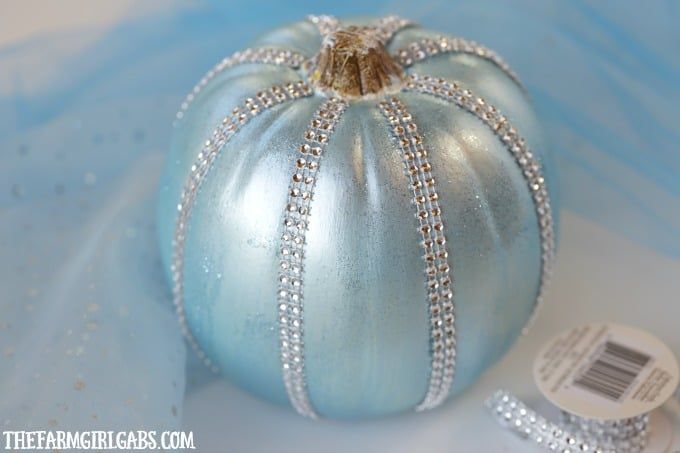 a small blue pumpkin with silver trimmings on it's sides and a tag next to it