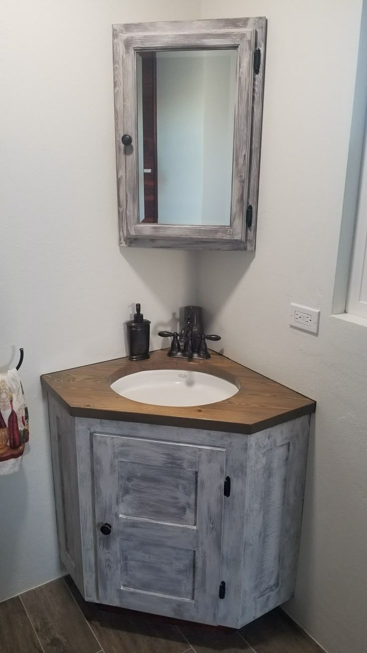 a bathroom with a sink, mirror and wooden cabinet in the corner on the wall