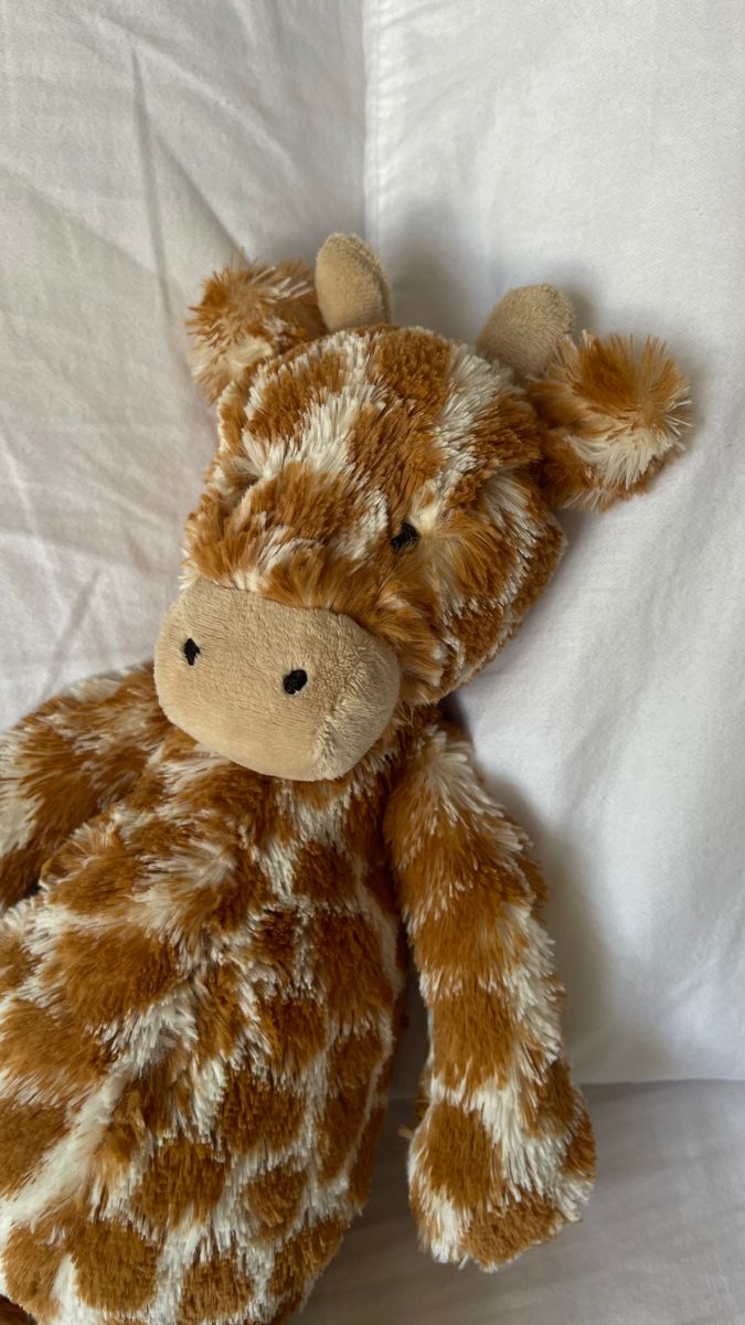 a brown and white stuffed animal laying on top of a bed