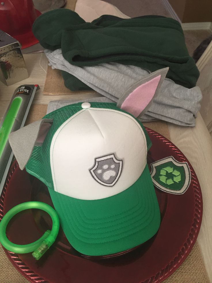 a green and white hat sitting on top of a plate next to a pair of scissors