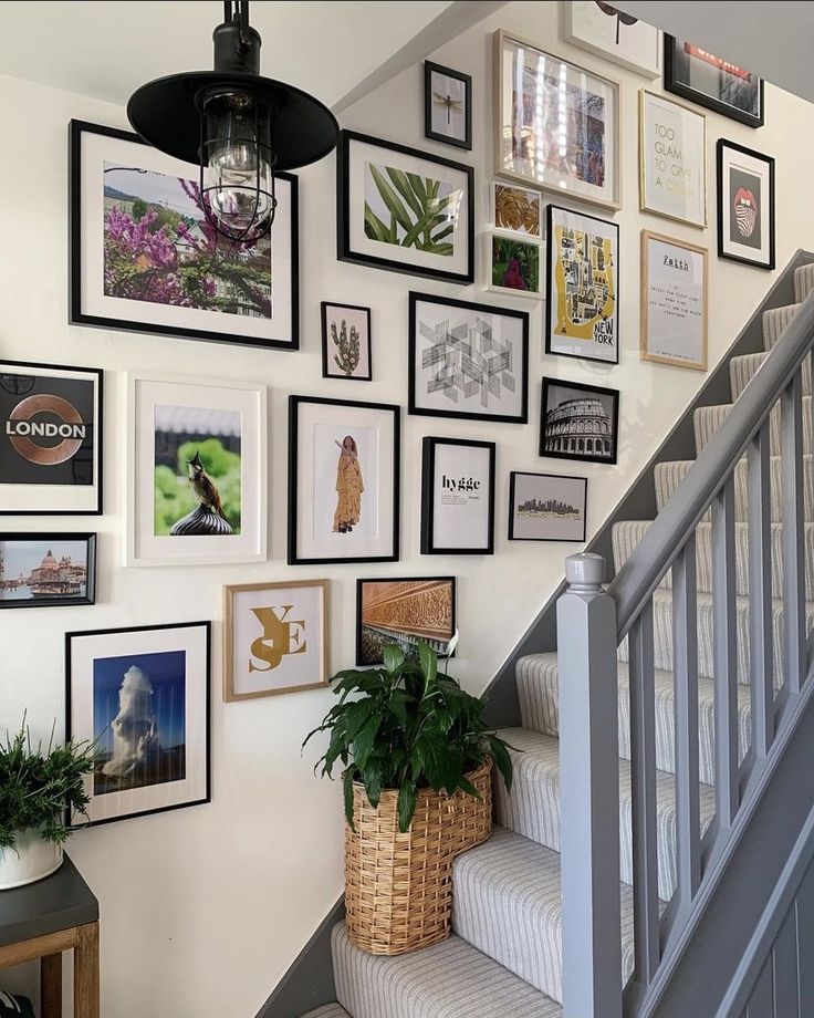 a staircase with pictures on the wall and a plant in a basket next to it