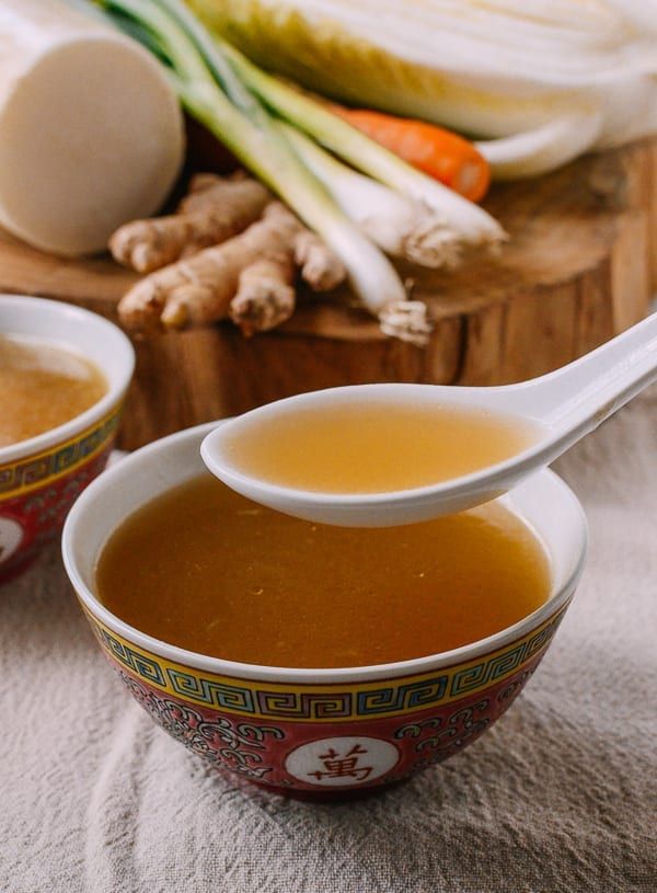 two bowls filled with soup sitting on top of a table next to sliced onions and carrots