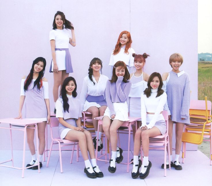 a group of young women sitting next to each other in front of a white wall