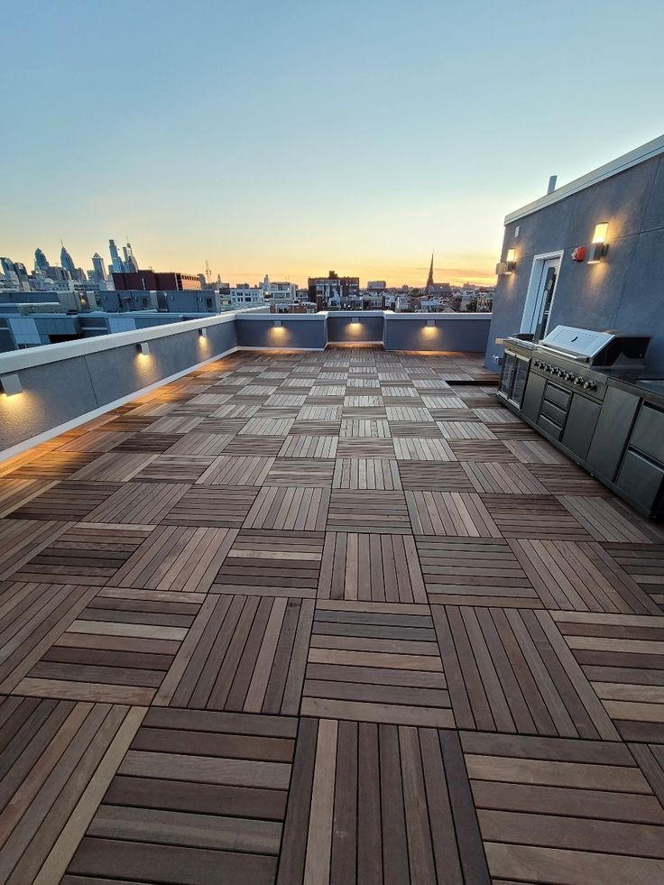 an outdoor kitchen on top of a roof with lights in the sky and buildings in the background