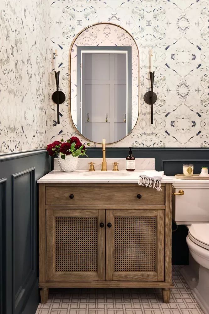 a white toilet sitting next to a wooden sink vanity in a bathroom under a mirror