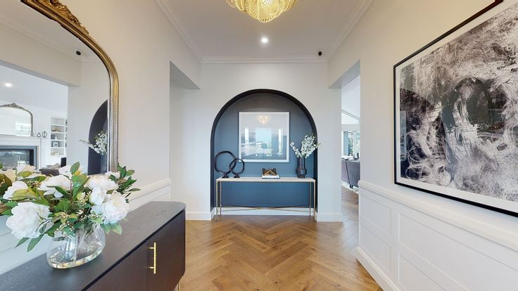 the hallway is decorated with white flowers and framed pictures on the wall, along with an entry way