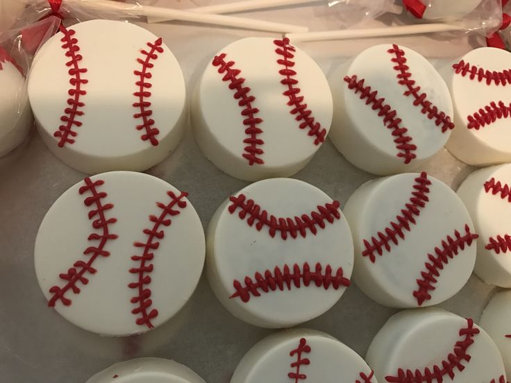 baseball themed cupcakes with white frosting and red piping on them are ready to be eaten