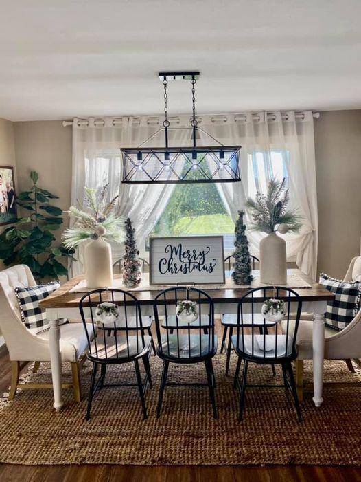 a dining room table with chairs and a christmas sign on the window sill above it