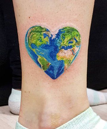 a heart shaped earth tattoo on the ankle, with an image of the world in it