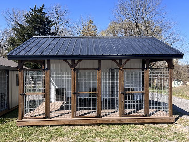 a small chicken coop in the middle of a yard with a metal roof and windows