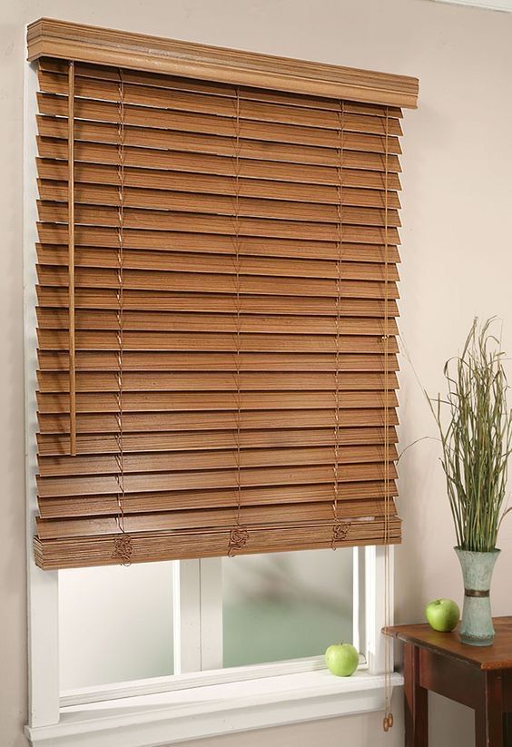 a window with wooden blinds in the corner and a potted plant next to it