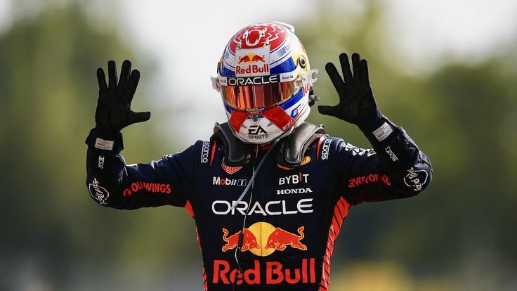 a man with his hands in the air wearing a red bull helmet and holding his arms up