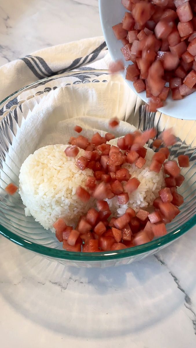 rice and red onions in a glass bowl on a marble counter top next to other food items