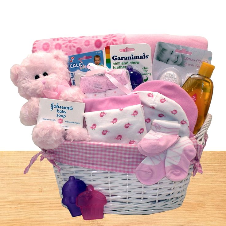 a pink teddy bear sitting in a white basket filled with baby goods and personal care items