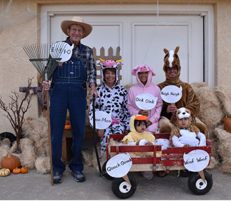 a group of people dressed up as farm animals in front of a house with scarecrows