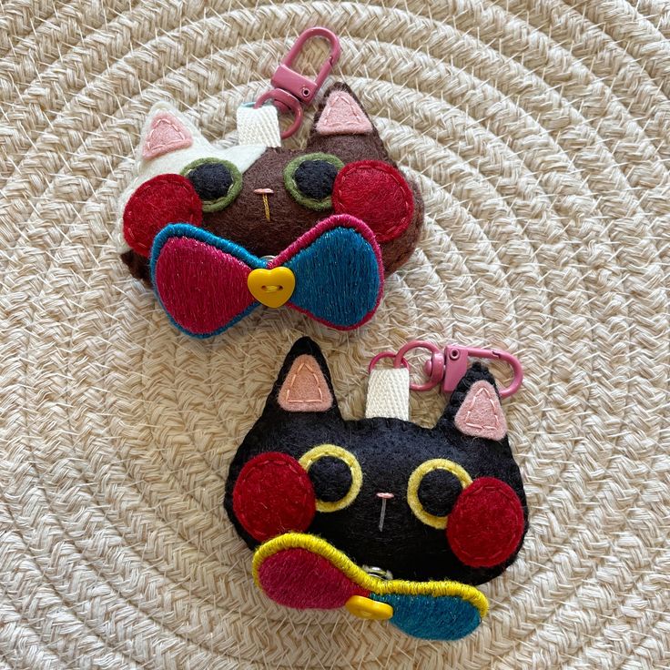 two black and white cat shaped purses sitting on top of a woven table cloth